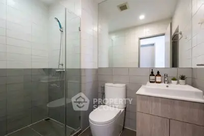 Modern bathroom with glass shower and sleek vanity in contemporary apartment.