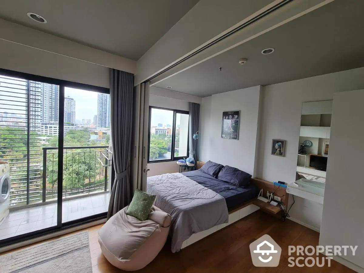 Modern bedroom with balcony and city view, featuring stylish decor and natural light.