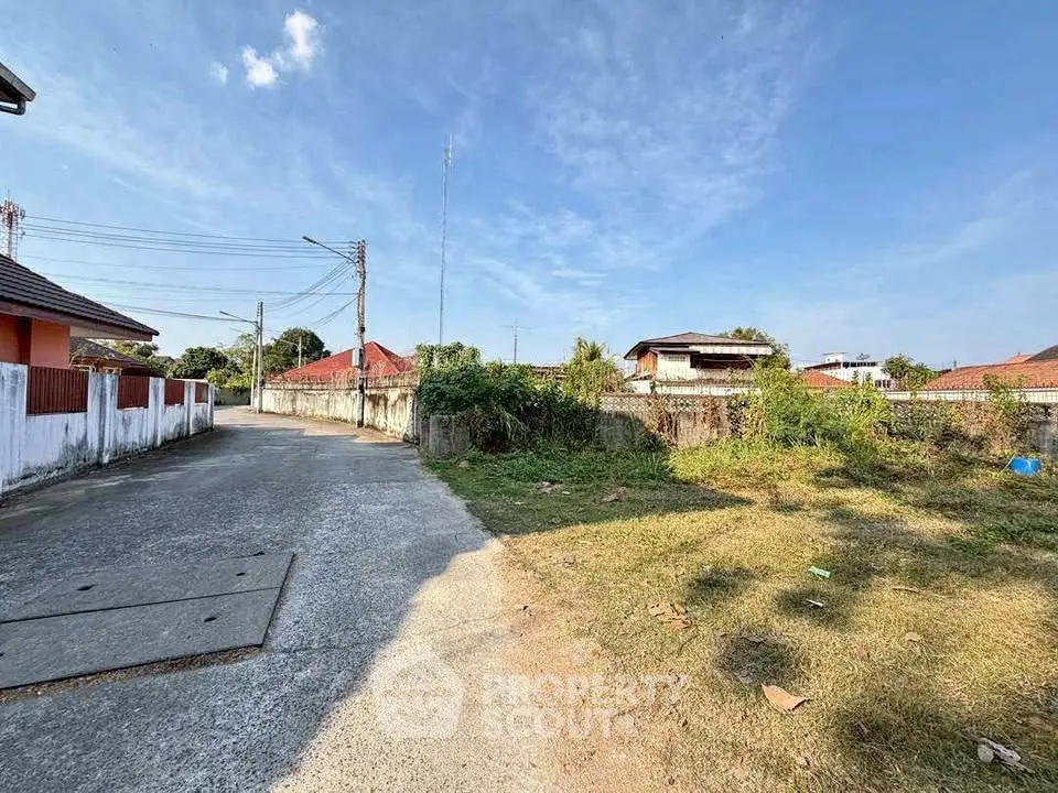 Charming suburban street view with clear blue sky and lush greenery, perfect for residential development.