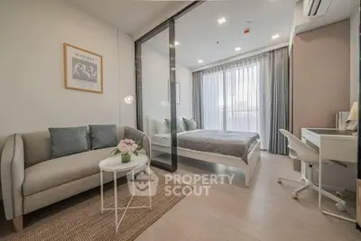 Modern bedroom with glass partition, cozy sofa, and study desk in stylish apartment.