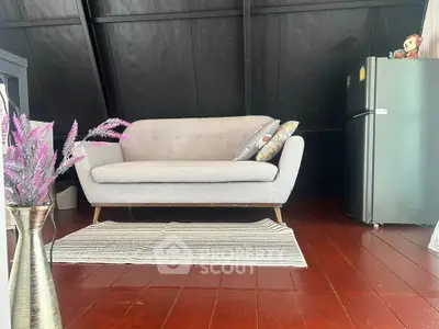 Cozy living room with modern sofa and fridge, perfect for compact living spaces.