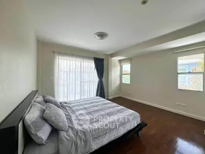 Spacious bedroom with large windows and elegant decor in a modern home.
