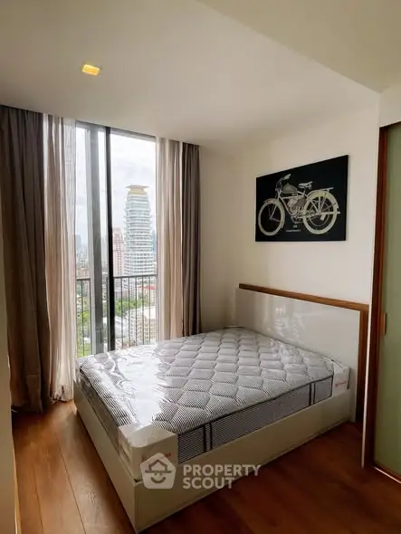 Modern bedroom with city view and stylish decor in high-rise apartment.
