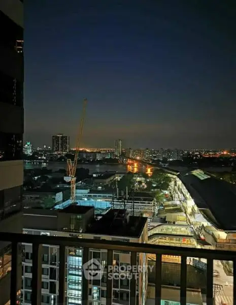 Stunning cityscape view from a high-rise balcony at night, showcasing urban skyline and construction crane.