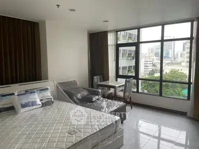 Spacious bedroom with large windows offering city views, featuring a bed and dining area.