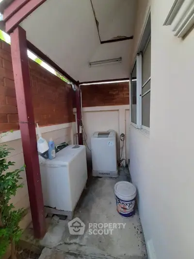 Outdoor laundry area with washing machine and freezer in a covered space.