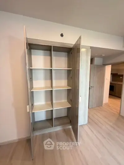 Spacious built-in storage cabinet in modern apartment with light wood flooring.