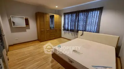 Spacious bedroom with wooden flooring and large wardrobe