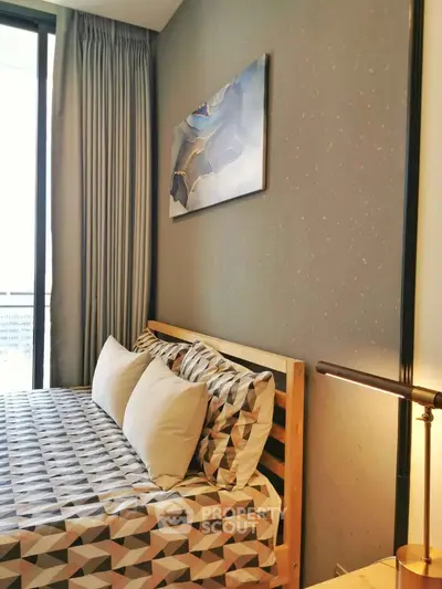Modern bedroom with stylish decor and large window offering natural light.