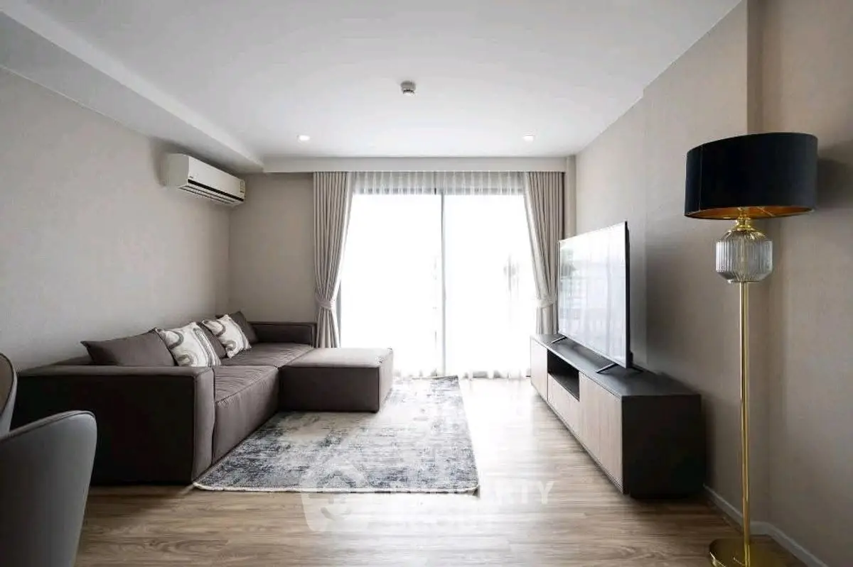 Modern living room with sleek furniture and large TV, featuring a cozy sofa and elegant floor lamp.