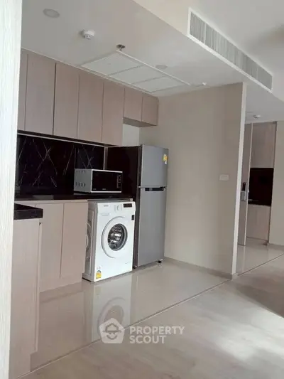 Modern kitchen with sleek appliances and washing machine in open layout