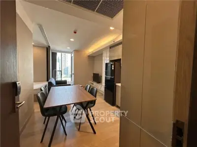Modern apartment interior with open layout dining and living area, featuring sleek furniture and city view.