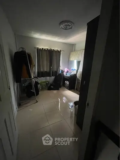 Cozy bedroom with natural light and tiled flooring, ideal for comfortable living.