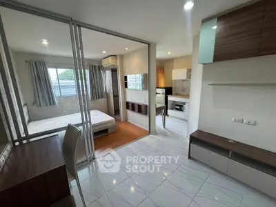 Modern studio apartment with glass partition, sleek kitchen, and cozy bedroom.
