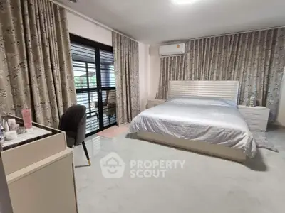 Spacious bedroom with elegant decor and large windows for natural light.