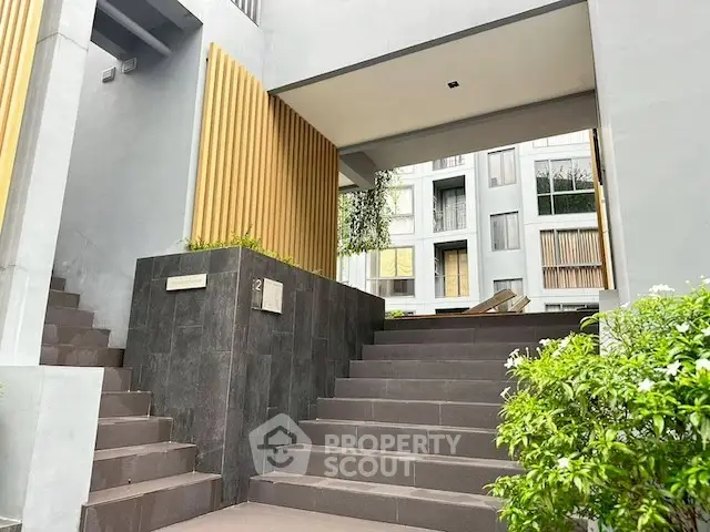 Modern apartment building entrance with sleek design and lush greenery