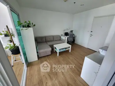 Modern living room with cozy sofa and study area, featuring wooden flooring and indoor plants.
