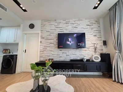Modern living room with stylish stone accent wall and mounted TV, featuring sleek black cabinetry and elegant decor.