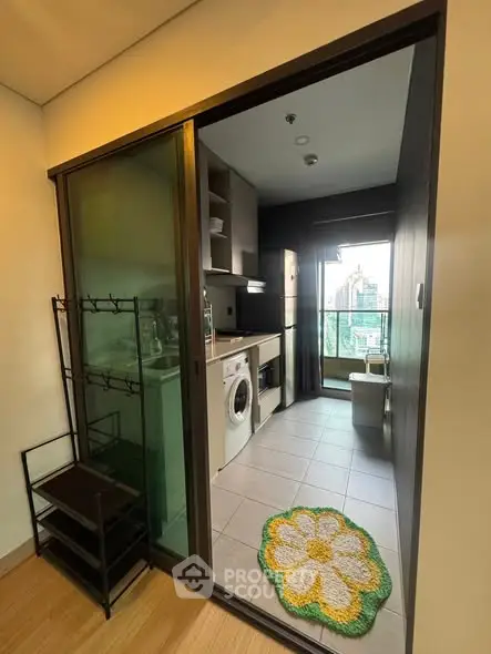 Modern kitchen with washing machine and city view, featuring sleek cabinetry and tiled flooring.