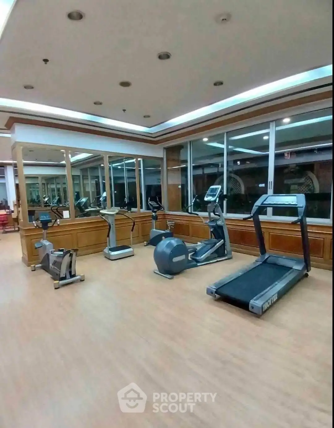 Spacious gym with modern fitness equipment and large mirrors in a luxury building.
