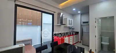 Modern kitchen with red cabinetry and open layout, adjacent to a small outdoor space.