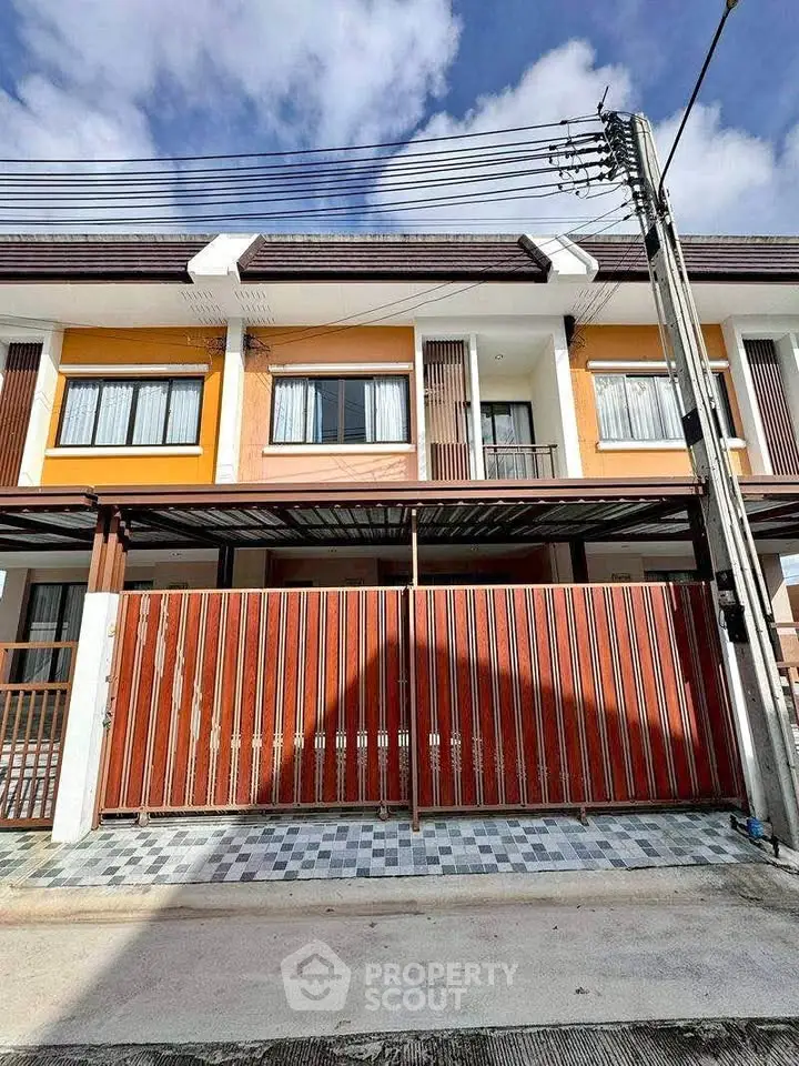 Modern townhouse exterior with gated entrance and tiled driveway under a clear blue sky.