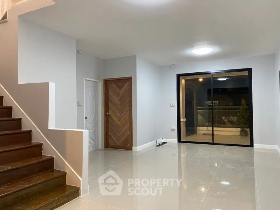 Spacious modern living room with sleek tile flooring and wooden staircase