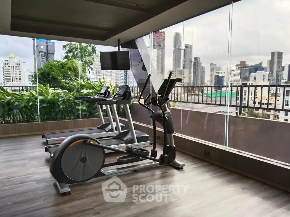 Modern gym with city view, featuring state-of-the-art exercise equipment and floor-to-ceiling windows.