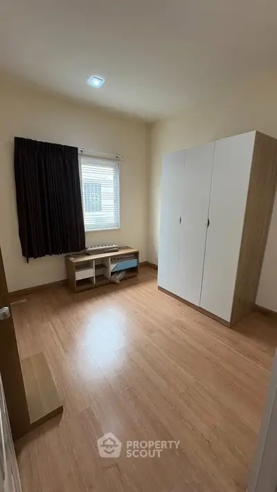 Spacious bedroom with wooden flooring and ample natural light.