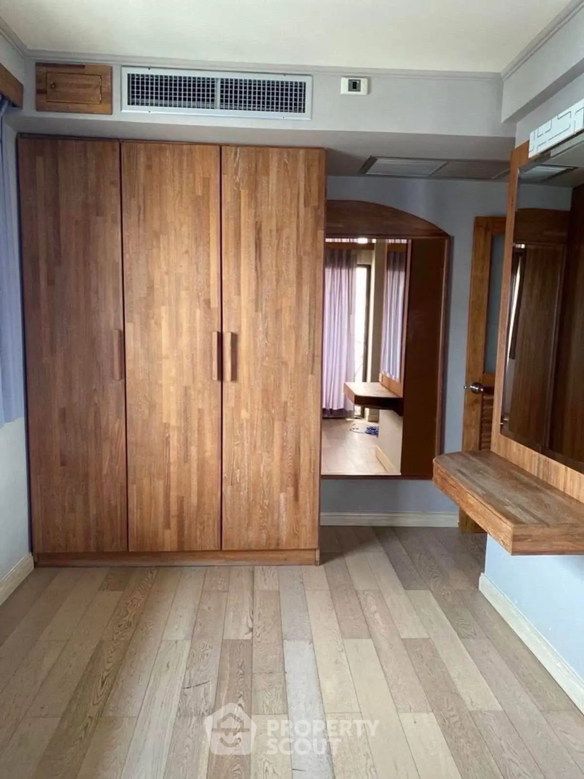 Spacious bedroom with wooden wardrobe and elegant flooring