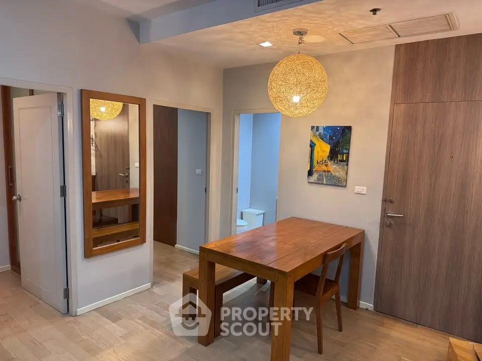 Modern dining area with wooden table and chairs, stylish lighting, and contemporary decor.