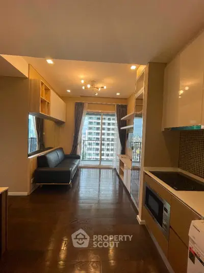 Modern apartment interior with sleek kitchen and spacious living area leading to balcony with city view.
