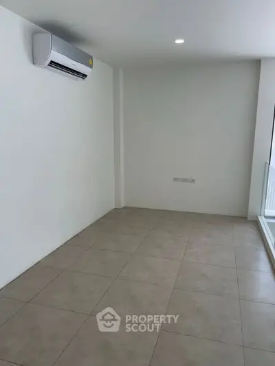 Spacious unfurnished room with air conditioning and large window, perfect for customization.