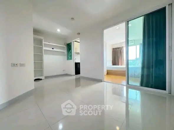 Spacious modern apartment with open layout and sliding glass doors leading to a bright bedroom.