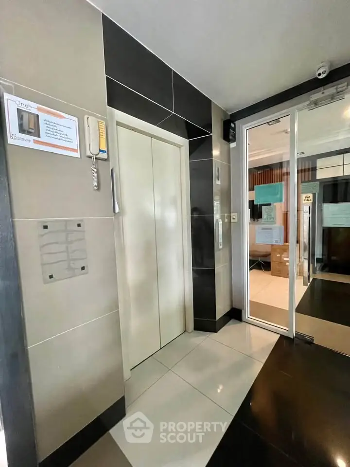 Modern building elevator lobby with sleek design and glass door entrance.