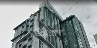 Modern high-rise building with sleek architectural design and large windows in urban setting.