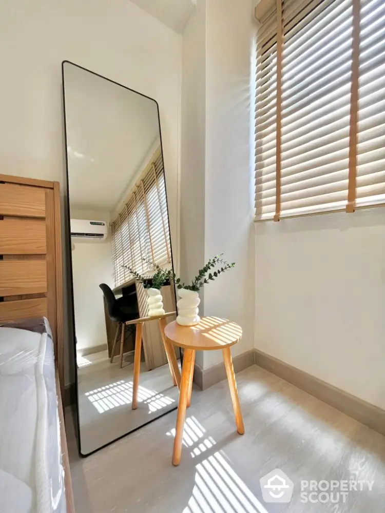 Bright bedroom corner with full-length mirror and wooden blinds