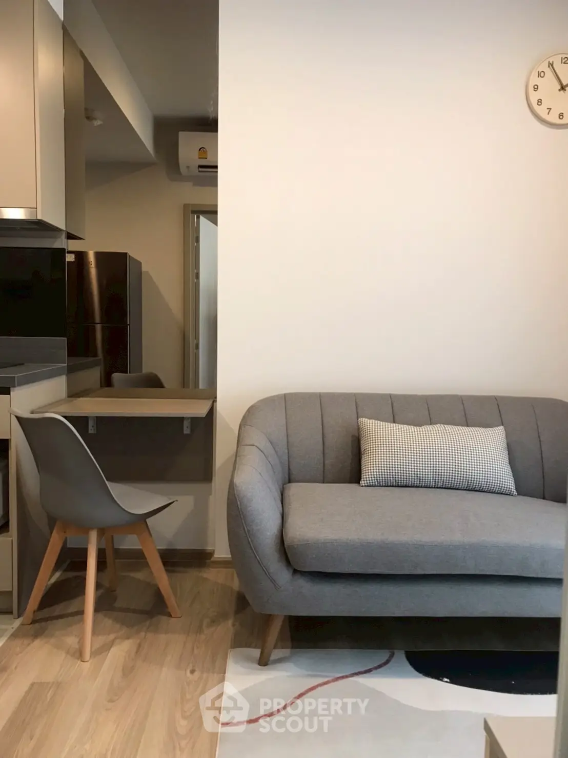 Modern living room with stylish gray sofa and wooden chair, featuring a minimalist design.