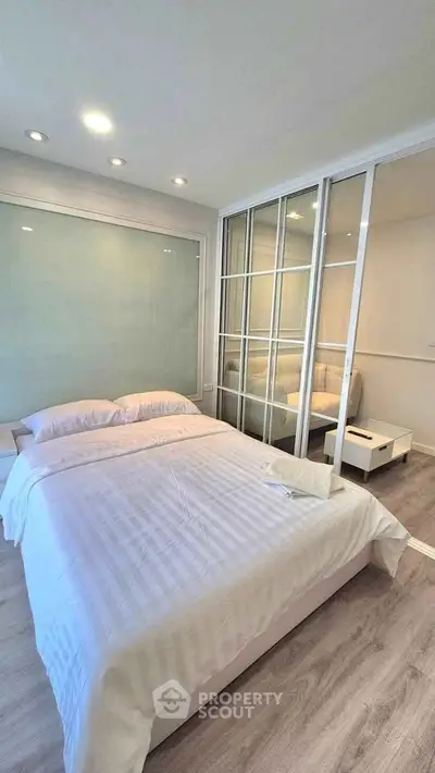 Modern bedroom with glass partition and cozy bedding in a stylish apartment.