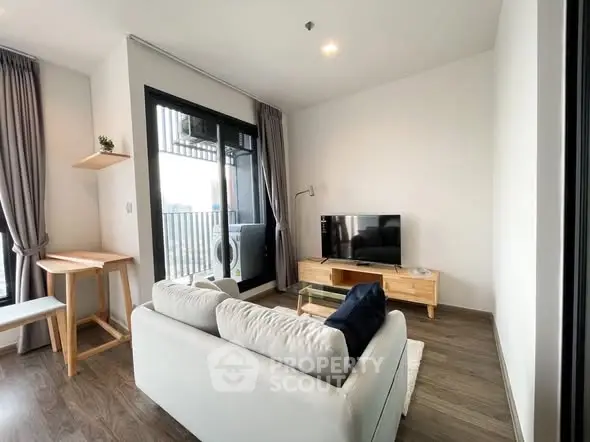 Modern living room with balcony, stylish furniture, and natural light.