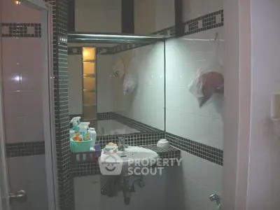 Compact bathroom with modern black and white tile design and small sink.