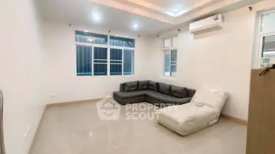 Spacious living room with modern sofa and air conditioning, perfect for relaxation.
