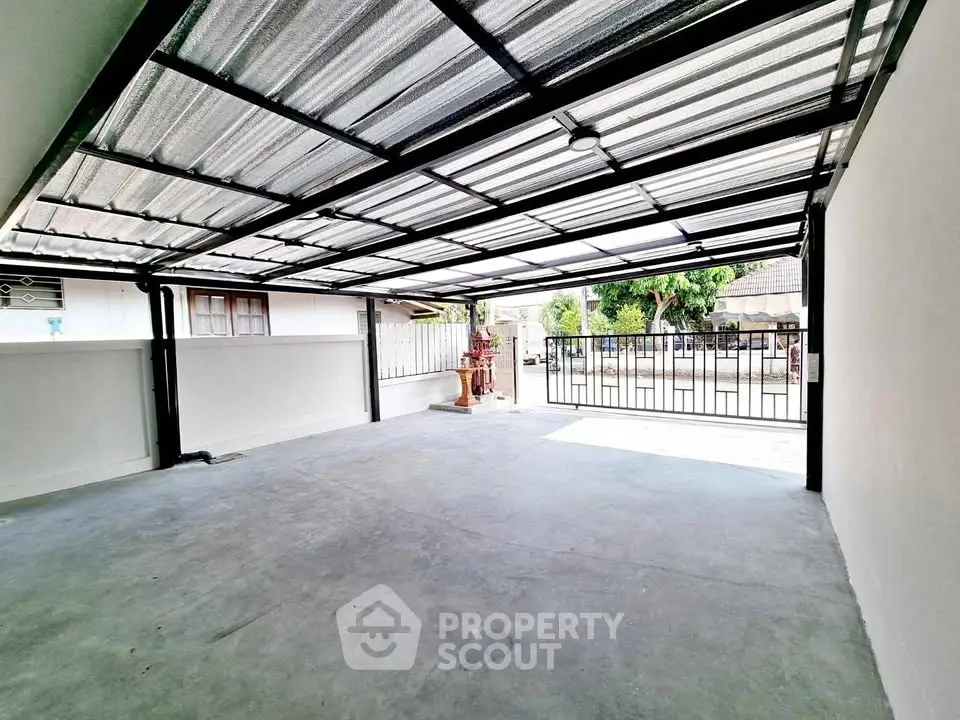 Spacious covered parking area with modern metal roofing and secure gate access.
