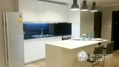 Modern kitchen with sleek white cabinets and island, featuring stylish pendant lighting.