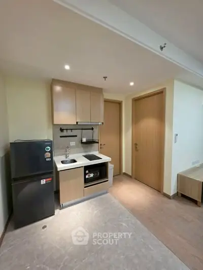 Modern compact kitchen with sleek cabinetry and built-in appliances in a cozy apartment setting.