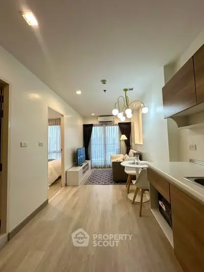 Modern open-plan living room with kitchen in stylish apartment, featuring elegant lighting and cozy decor.