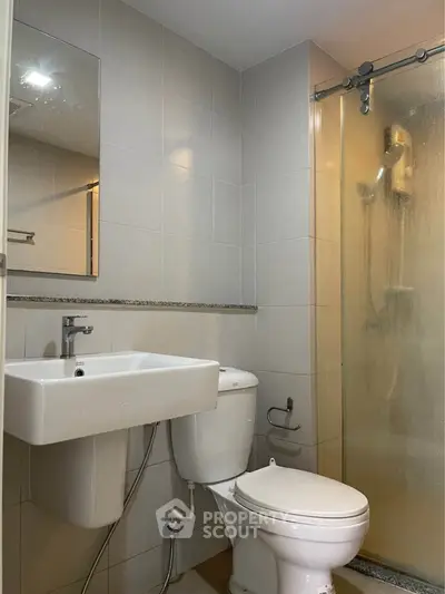 Modern bathroom with sleek fixtures and glass shower enclosure in a contemporary apartment.