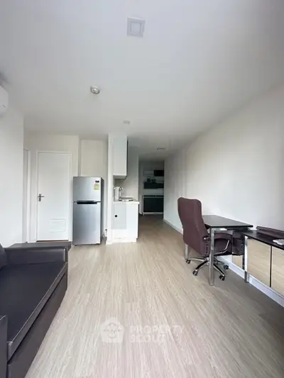 Modern apartment interior with open layout, featuring a cozy living area and compact kitchen.