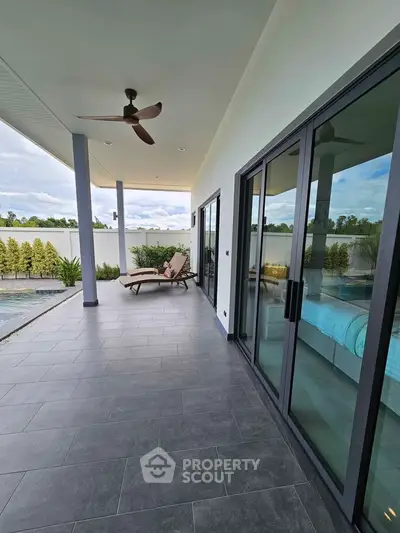 Spacious modern balcony with pool view and lounge chairs, perfect for relaxation.