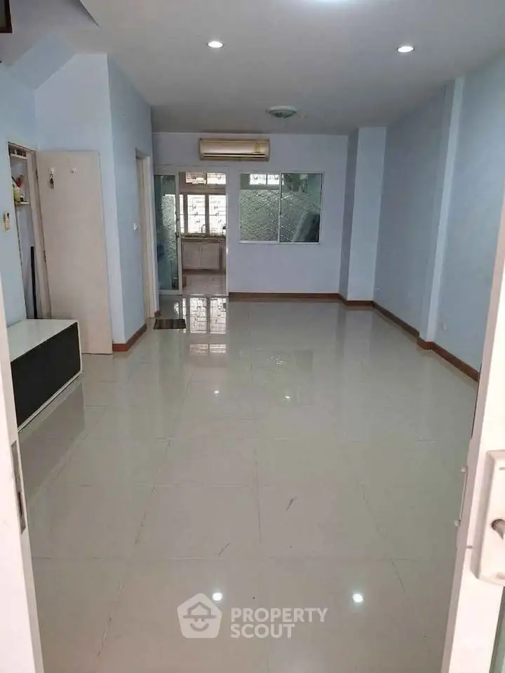 Spacious empty living room with glossy tiled floors and large window for natural light.